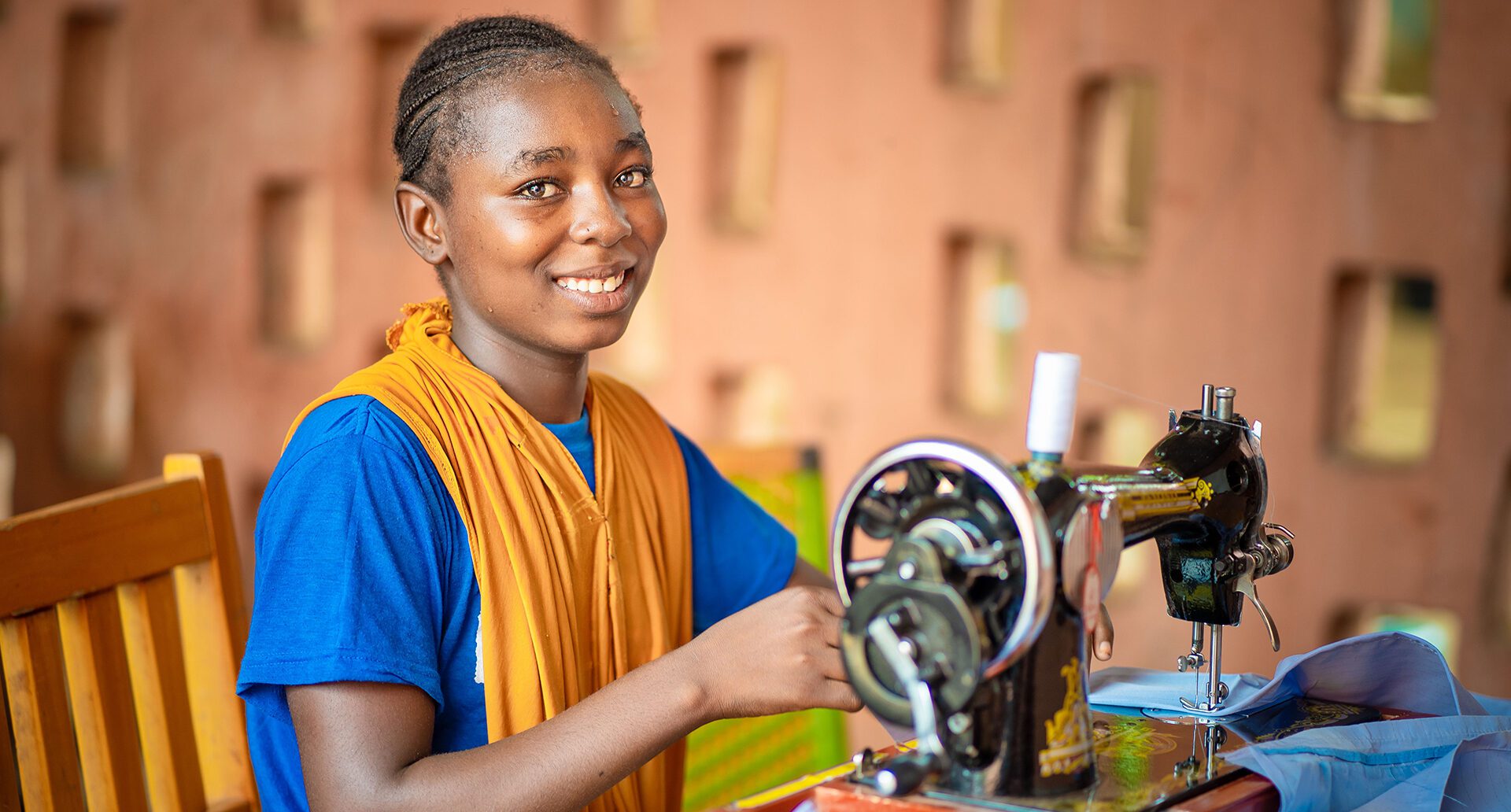 African woman teaching vocational skills to young adults in a workshop